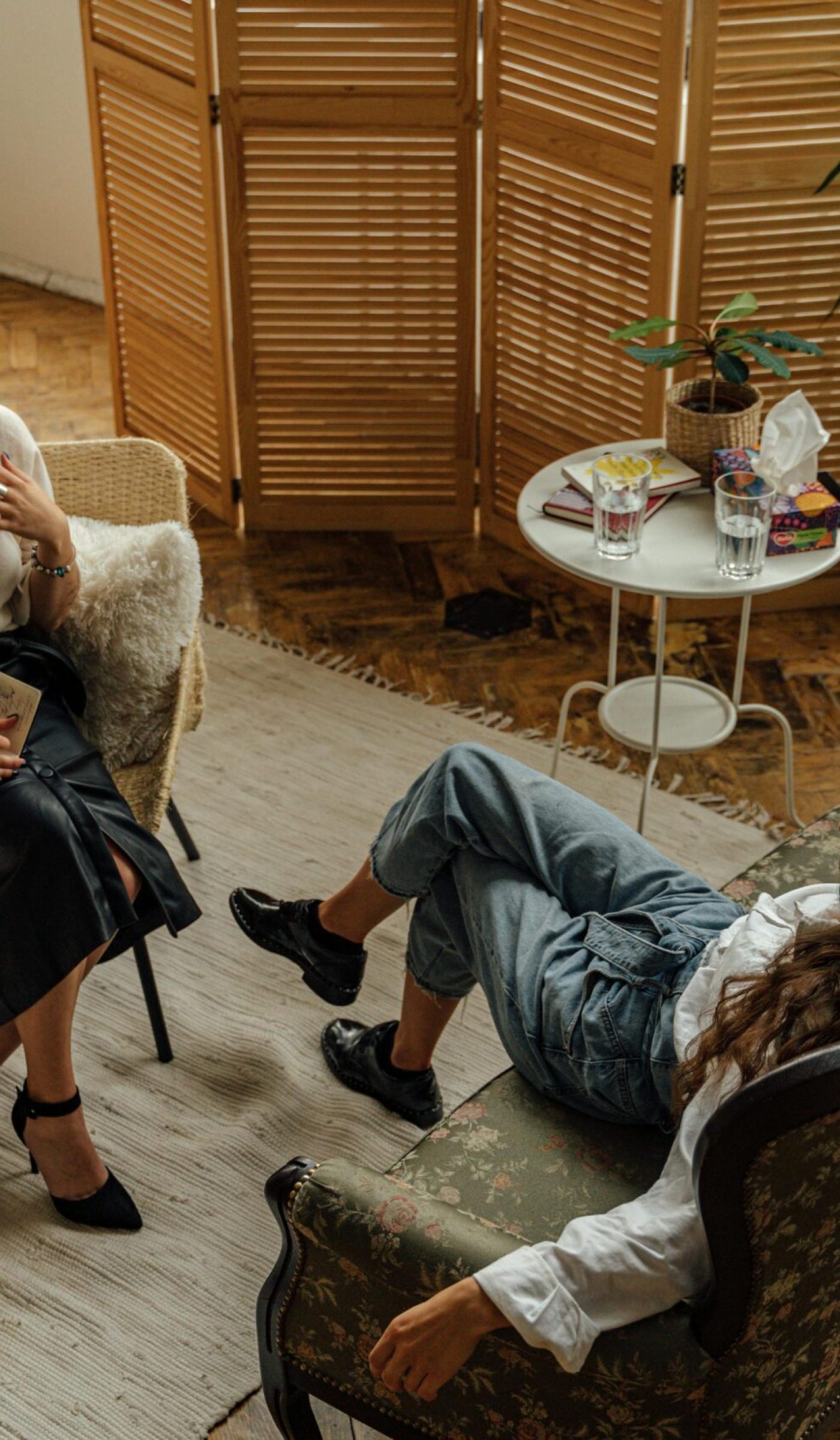 pexels-photo-5217852-5217852 Two women engaged in a psychotherapy session in a warm, inviting interior with plants and natural lighting.